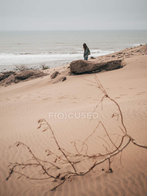 Женщина, идущая по берегу у океана — стоковое фото