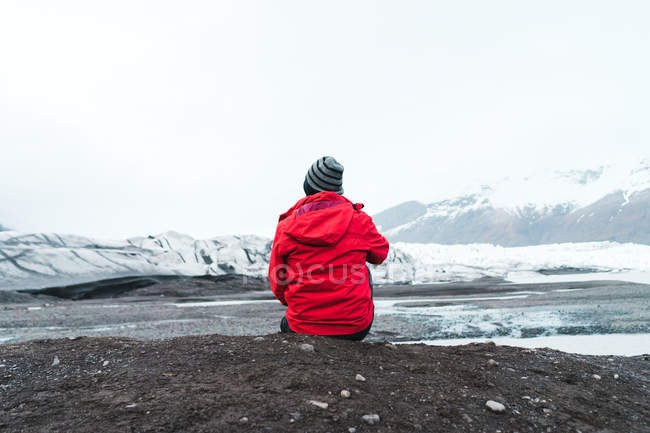Человек, сидящий у воды в горах — стоковое фото