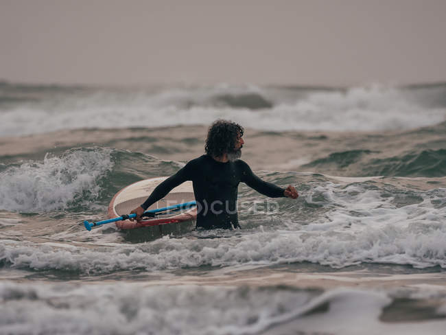 Man with paddle board in ocean — Stock Photo
