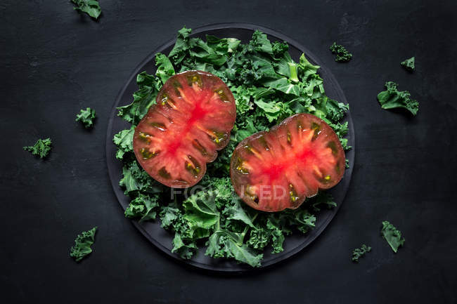 Tomates coupées en deux sur la laitue — Photo de stock