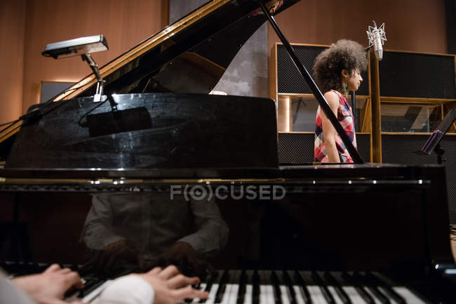 Mãos masculinas tocando piano perto do vocalista — Fotografia de Stock