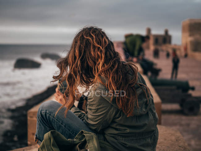 Femme assise au bord de la mer — Photo de stock