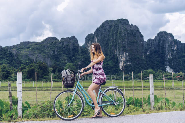 Mujer bonita en bicicleta en el camino rural - foto de stock