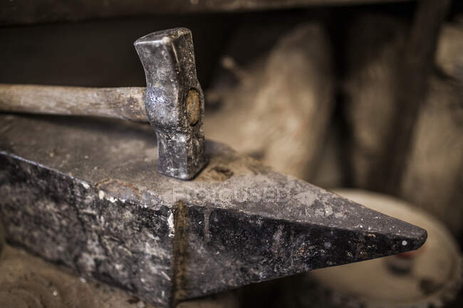 Crop close-up view of hammer lying on metal anvil in casting factory — Stock Photo