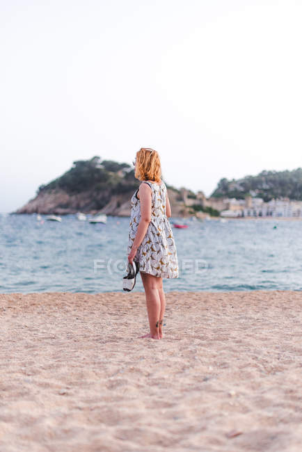 Mulher carregando sandálias na praia — Fotografia de Stock
