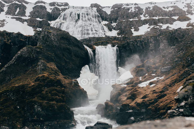 Waterfall flowing from gloomy black rocks — Stock Photo