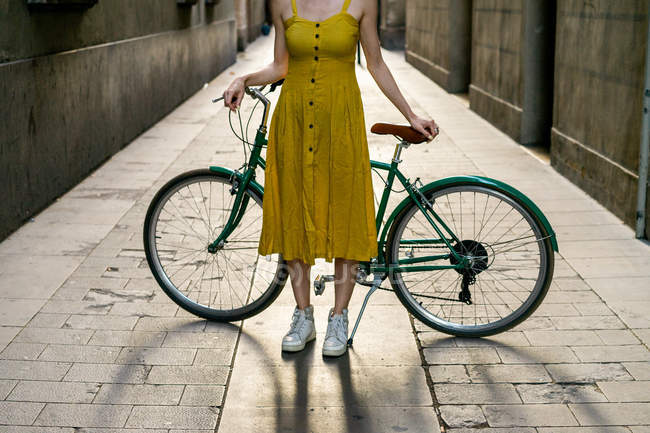 Женщина, стоящая на улице с велосипедом — стоковое фото