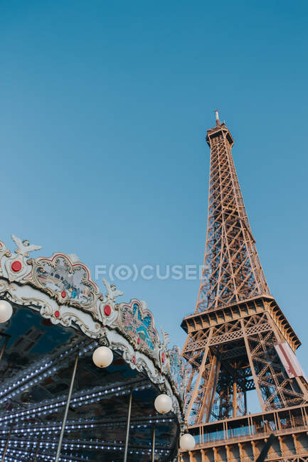 Colorido carrusel y torre Eiffel frente al cielo despejado en París, Francia - foto de stock