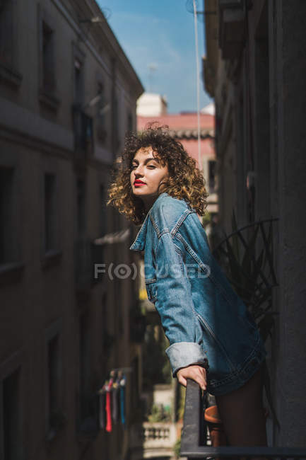 Donna in piedi sul balcone sotto il sole — Foto stock
