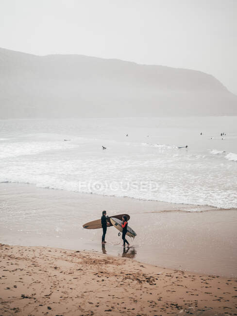 Due surfisti con tavole sulla costa — Foto stock