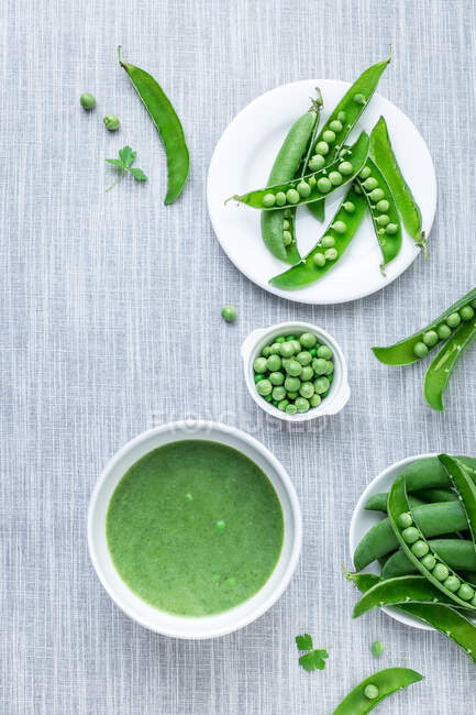 From above peeled peas from pods and green cream soup on table. — Stock Photo