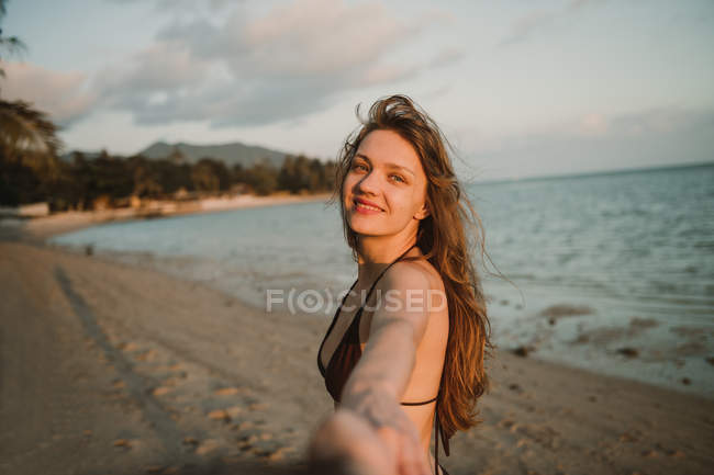 Женщина держит фотографа за руку на пляже — стоковое фото