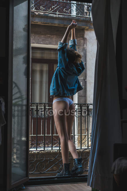 Frau in Jeansjacke steht auf Balkon — Stockfoto