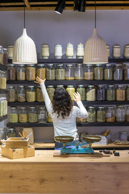 Femme prenant pot avec épice dans le magasin — Photo de stock