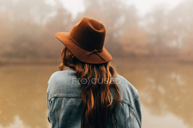 Mulher usando chapéu de pé na lagoa — Fotografia de Stock