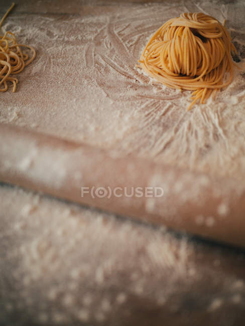 Tangled spaghetti on table with flour — Stock Photo