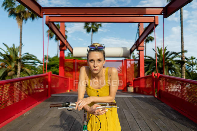 Жінка в літньому одязі спирається на велосипед — стокове фото