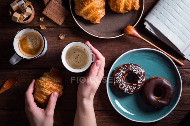 Mains avec café et croissant — Photo de stock
