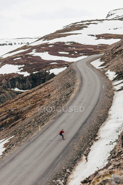 Veduta aerea del viaggiatore pattinaggio a cavallo su lunga strada remota in montagne innevate d'Islanda. — Foto stock