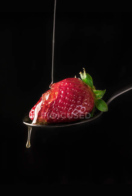 Strawberry in pouring honey — Stock Photo