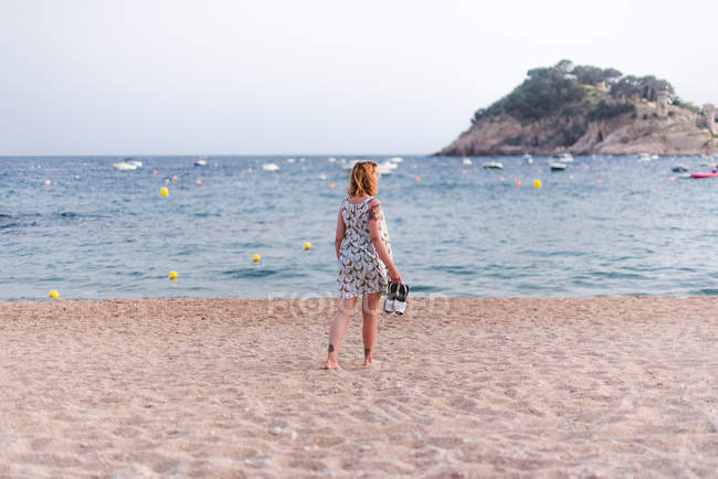 Mujer llevando sandalias en la playa - foto de stock