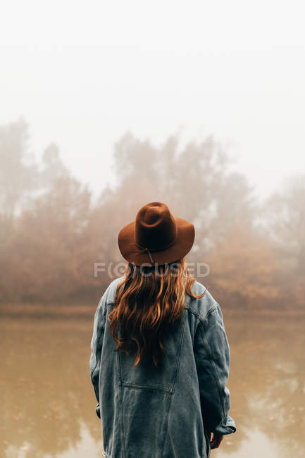 Femme portant un chapeau debout à l'étang — Photo de stock