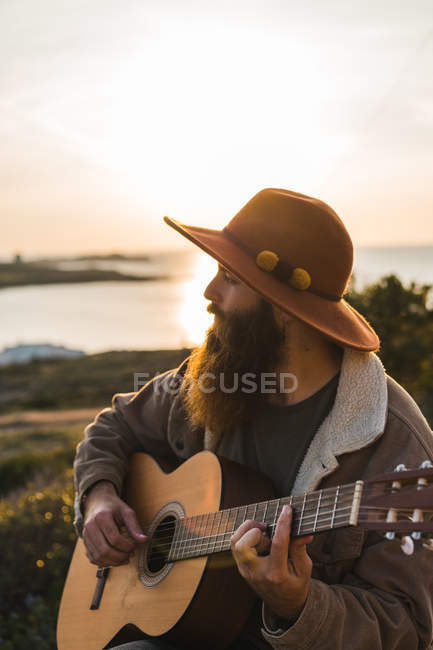 Man playing guitar on rock — Stock Photo