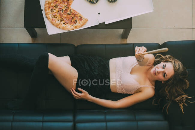 Жінка лежить на дивані з марихуанським суглобом — стокове фото