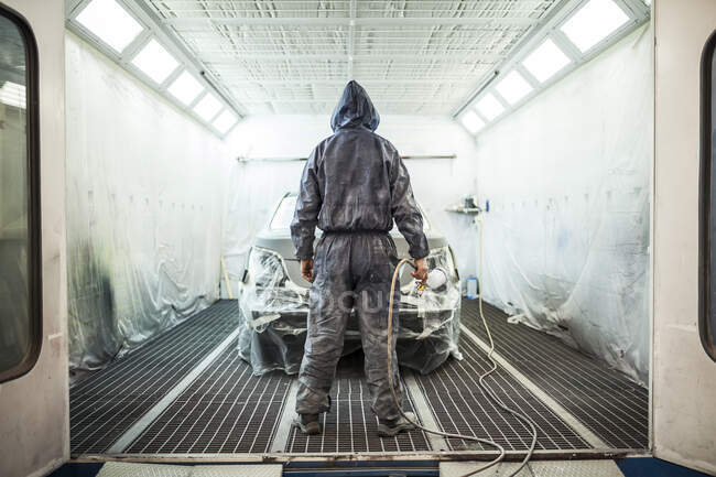 Painter posing in front of the booth before painting a car — Stock Photo