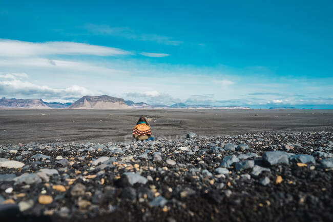 Rückansicht einer jungen Frau, die in einer atemberaubenden Landschaft steht und die Aussicht genießt, während sie durch Island reist — Stockfoto