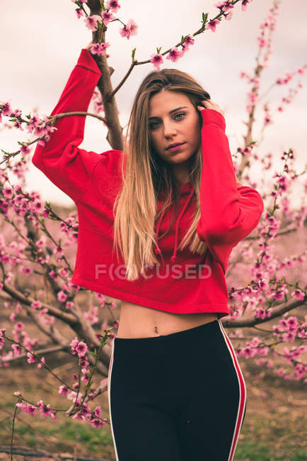 Woman standing next to blooming tree — Stock Photo