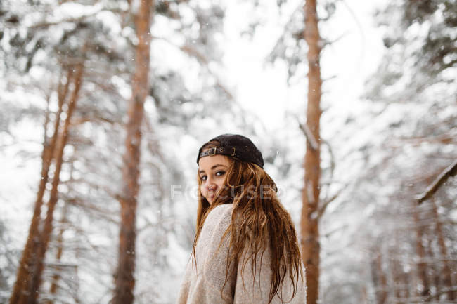 Mulher olhando para trás na floresta nevada — Fotografia de Stock