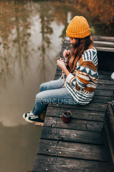 Woman sitting and knitting at pond — Stock Photo