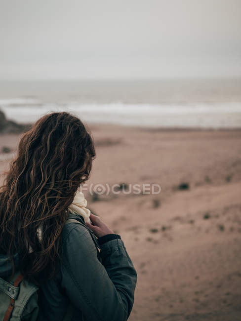 Femme avec sac à dos debout à l'océan — Photo de stock