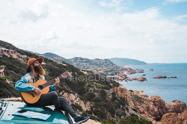 Uomo che suona la chitarra sul tetto dell'auto — Foto stock