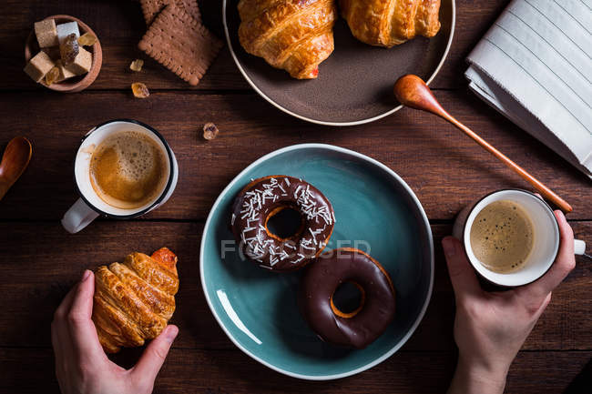 Mains avec café et croissant — Photo de stock