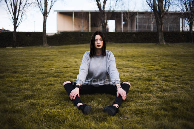 Frau sitzt auf Gras und blickt in Kamera — Stockfoto