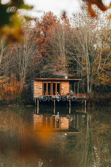 Жінка сидить на ганку дерев'яної хатини — стокове фото
