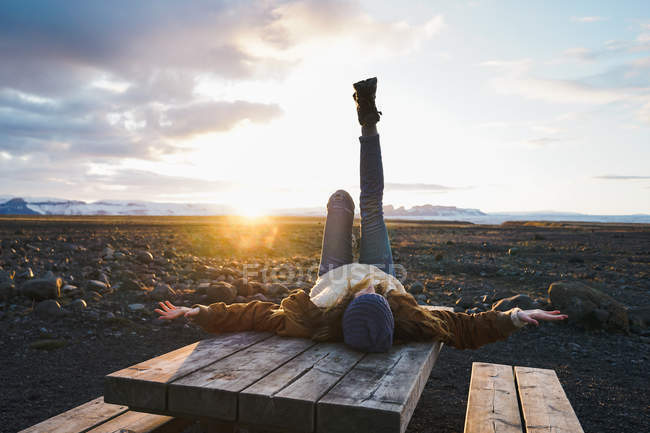 Frau liegt bei Sonnenuntergang auf Holztisch — Stockfoto