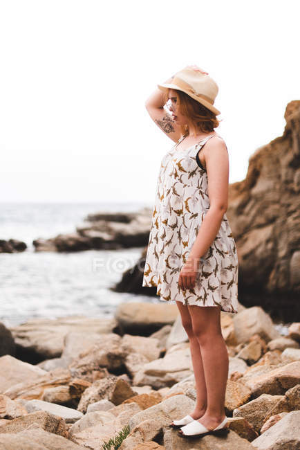 Femme avec chapeau debout sur des rochers — Photo de stock