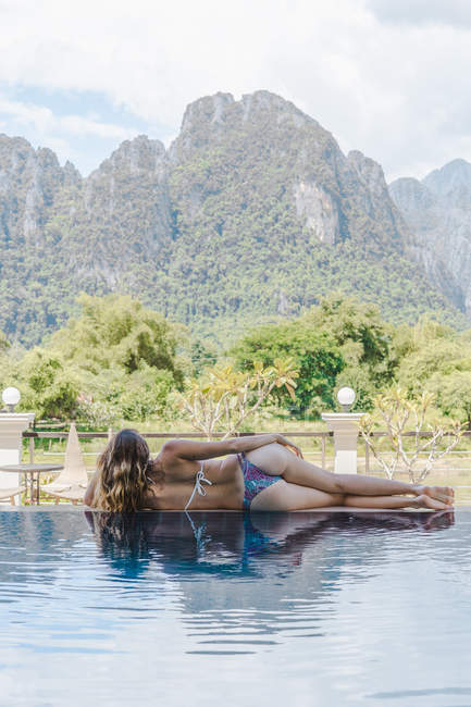 Woman in bikini lying at poolside — Stock Photo