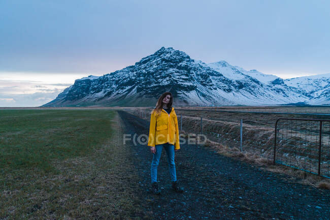 Женщина на дороге к заснеженной горе — стоковое фото