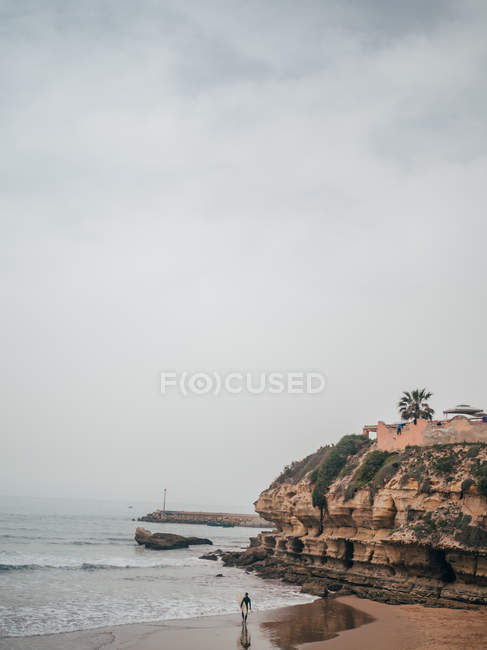 Surfer walking on sandy beach — Stock Photo