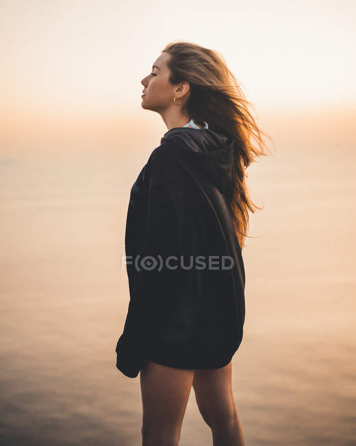 Mulher de pé no mar e olhando para longe — Fotografia de Stock