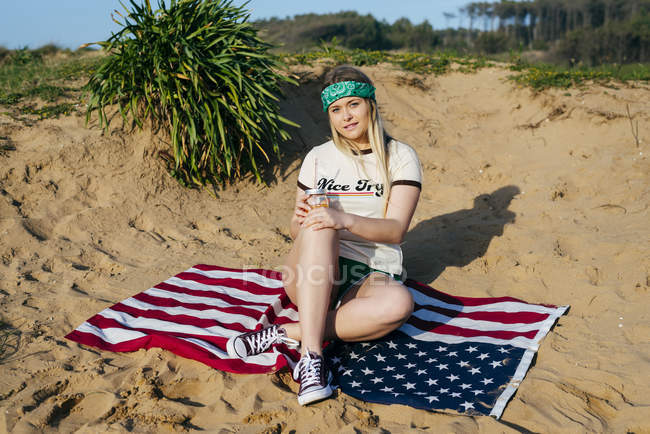 Menina com bebida sentado na bandeira americana — Fotografia de Stock