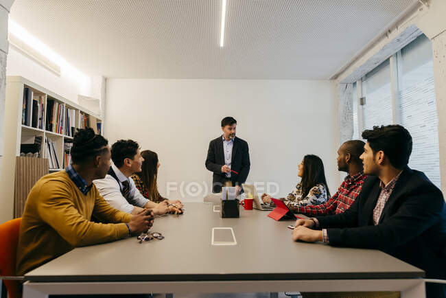 Многорасовые мужчины и женщины, работающие в офисе, сидят в офисной комнате. — стоковое фото