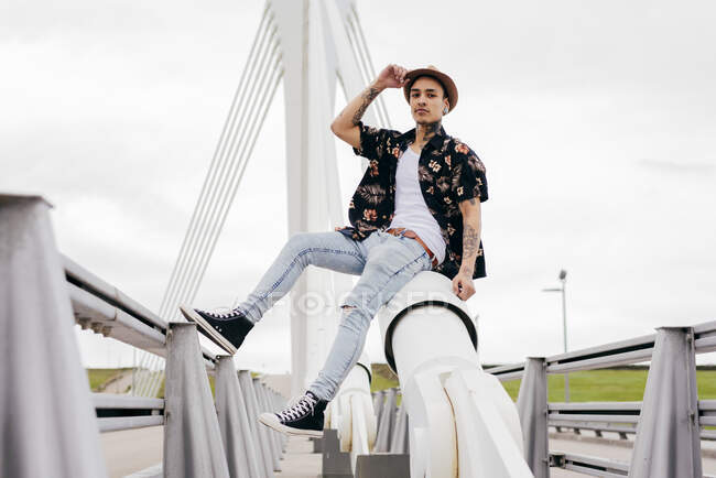 Hipster seduto su ringhiera di ponte — Foto stock