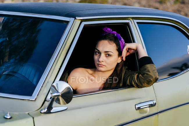 Mujer sentada en coche vintage - foto de stock