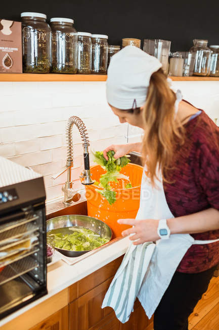 Женщина стирает салат в раковине — стоковое фото