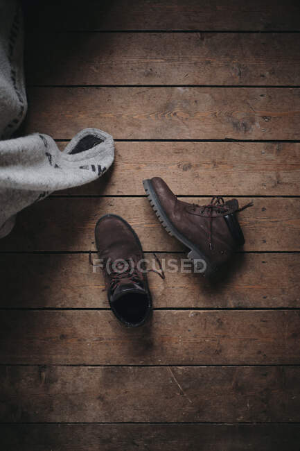 Desde arriba botas de cuero marrón desatadas quitadas en el suelo de madera - foto de stock